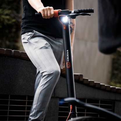 The Commuta Scooter - A close up shot of a man standing on the scooter, holding on with one arm. 