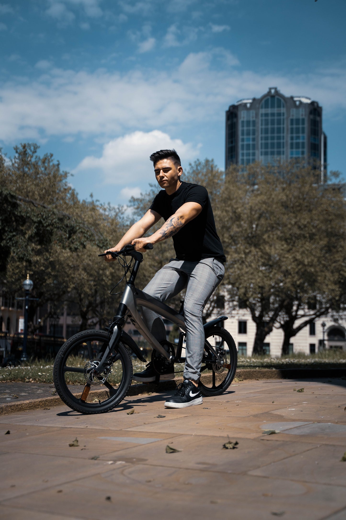 The Cruzaa E-Bike in Gunmetal Grey with rider in a city landscape. 