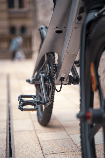 The Cruzaa E-Bike in Gunmetal Grey. Detail of the pedal and chain from behind. 